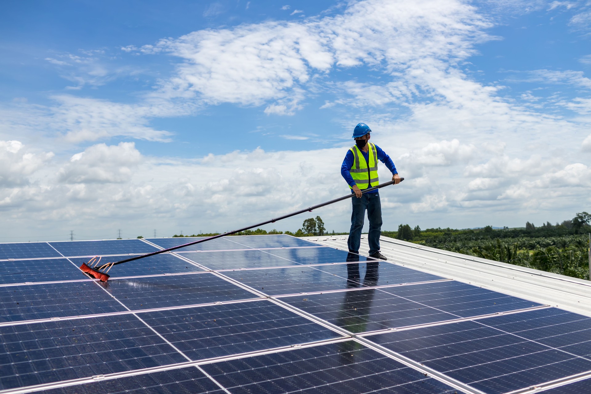 Worker Cleaning solar panels with brush and water. Worker cleaning solar modules in a Solar Energy Power Plan